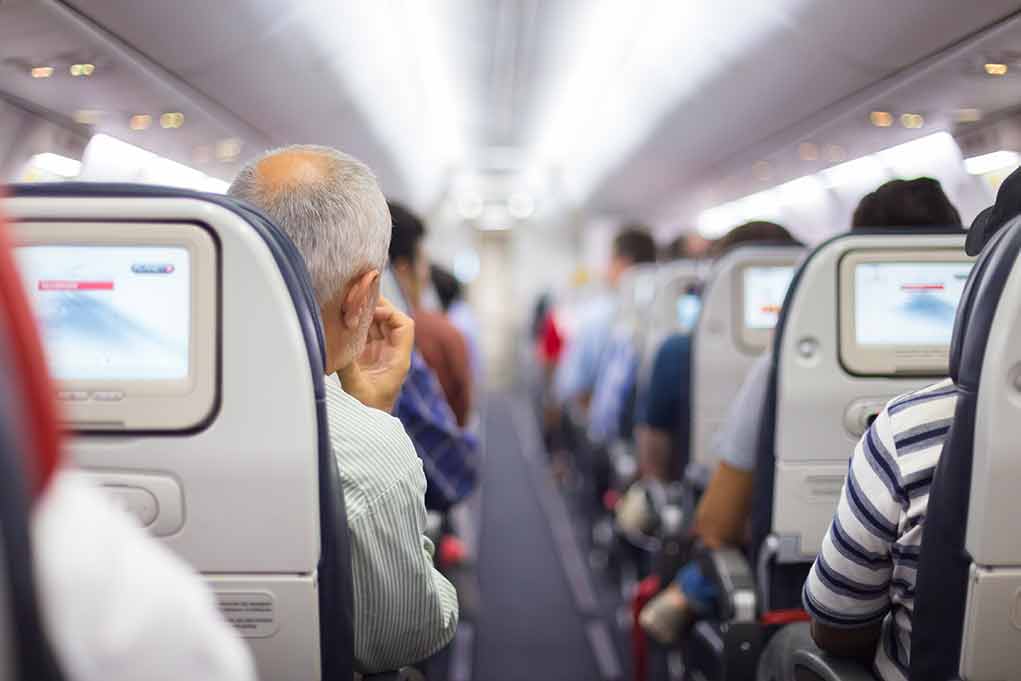 Passengers sitting in airplane seats with screens.