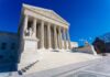 Supreme Court building with columns and statues.