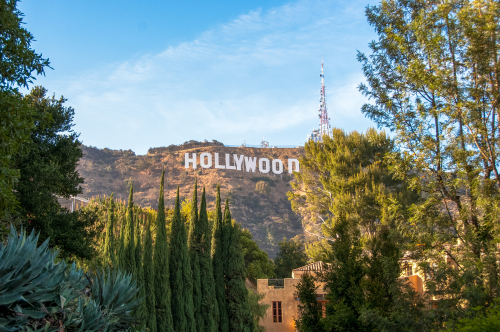 Hollywood Sign on hillside surrounded by trees, clear sky.