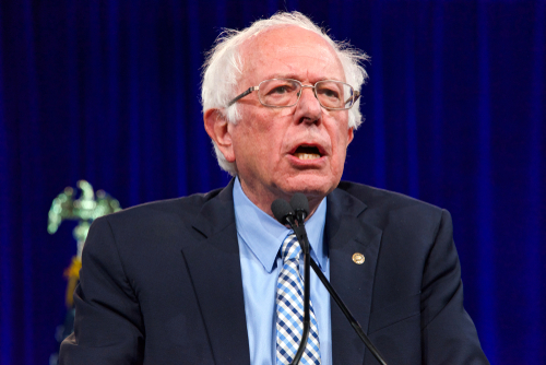 Bernie Sanders speaking at an event, wearing a suit.