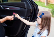 Child being handed candy by person in car.