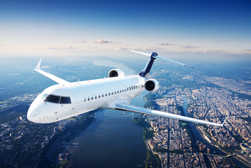 Airplane flying over a city with a river below.