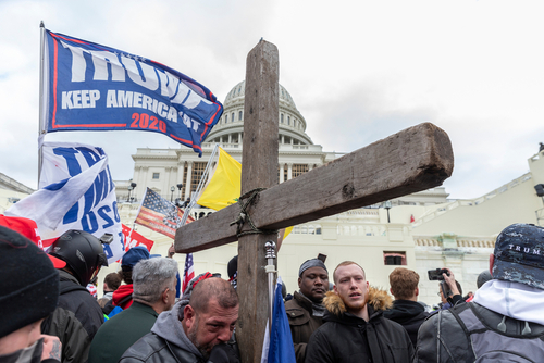 Protesters with Trump flag and cross outside the Capitol building.