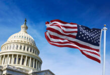 U.S. Capitol building with American flag waving in foreground.