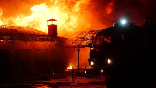 Firefighters combat blaze at burning building at night.