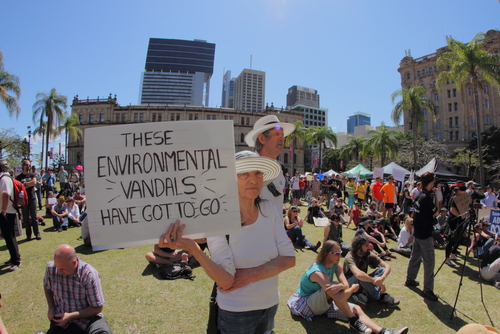 People at a protest, holding sign about environmental vandals.