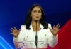 Person speaking at a podium with hands raised