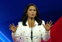 Person speaking at a podium with hands raised