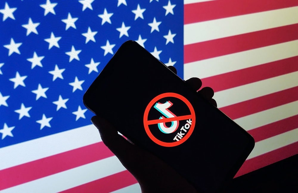 Phone showing TikTok banned symbol USA flag background