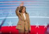 Woman waving in front of American flag backdrop