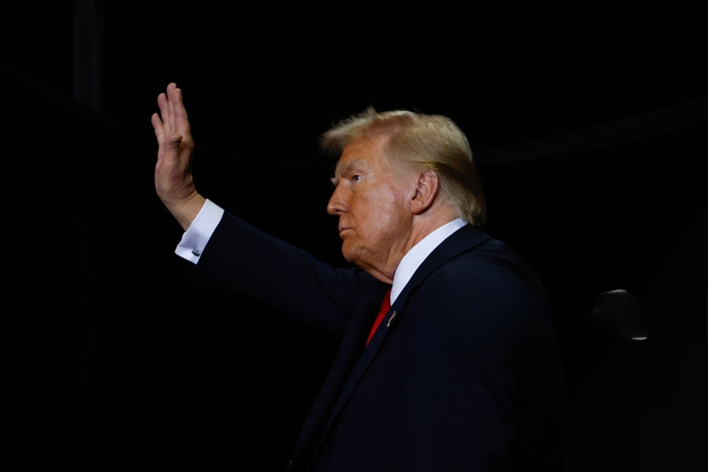 Person in suit raising hand in dark setting