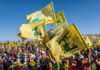 People waving Hezbollah flags at a large outdoor gathering.