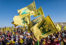 People waving Hezbollah flags at a large outdoor gathering.