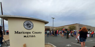 Protest outside Maricopa County elections building with signs.