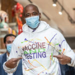 Political Revenge? MAMDANI Cuts Off Adams’ Legal Lifeline… Man wearing Vaccine and Testing hoodie, pointing at text.