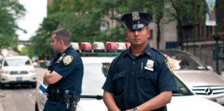 Two NYPD officers standing near a police car in an urban environment