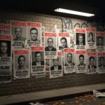 Eight Defense Scientists VANISHED — Targeted Elimination? Wall covered with missing persons posters in an urban setting