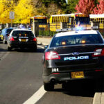 School Buses Turned Big Brother Spy Machines? Police cars and school buses on a sunny street.
