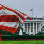White House FIGHT Night: Patriotic Showcase or Managed Optics? American flag waves before the White House on a cloudy day