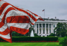 White House FIGHT Night: Patriotic Showcase or Managed Optics? American flag waves before the White House on a cloudy day
