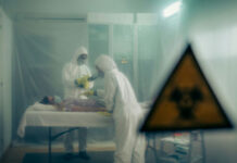 Ebola RISING: Rubio’s America-First Gamble… Two scientists examining a patient with biohazard sign visible.