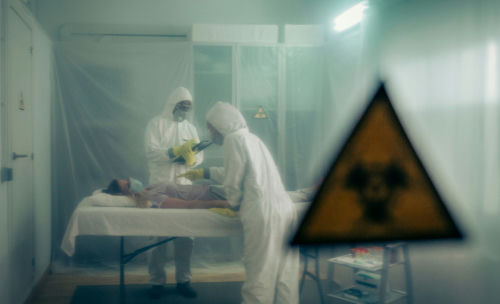 shutterstock1556490968-1jpg Two scientists examining a patient with biohazard sign visible.