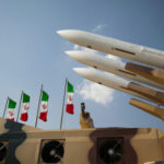Missiles on launchers beside Iranian flags.