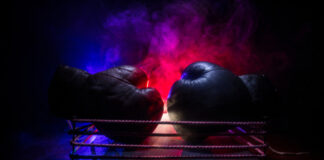 Two boxing gloves positioned in a ring with dramatic lighting and smoke