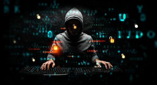 shutterstock_1480095632 Hacker in hoodie surrounded by digital symbols and locks.