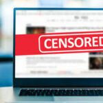 Laptop screen with CENSORED banner over webpage