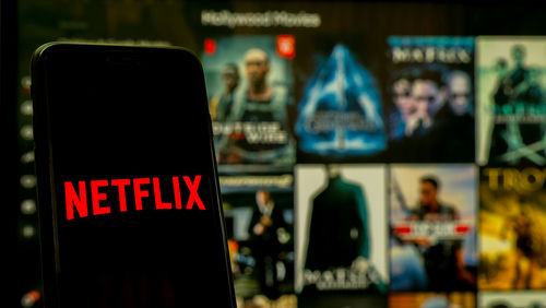 shutterstock_1896570715.jpg Netflix app open on phone; Hollywood movies in background.