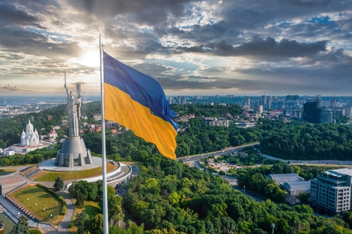 Kyiv,,Ukraine.,July,10,,2021.,Aerial,View,Of,The,Ukrainian Ukrainian flag waving in front of a monument with a city skyline in the background