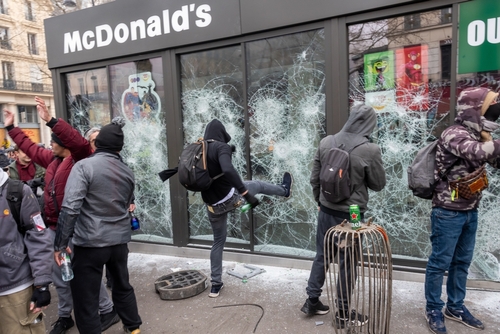 Protesters vandalizing a McDonald's restaurant with broken windows