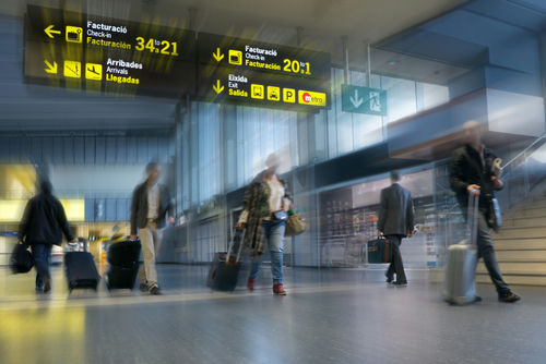 shutterstock_233004307 Travelers with rolling suitcases walk through an airport terminal
