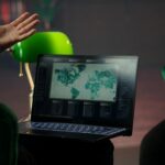 Person gesturing towards a laptop displaying a world map and data analytics