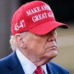 Trump’s Wedding SNUB — Iran Crisis Excuse? A man wearing a red cap with a political slogan, looking serious
