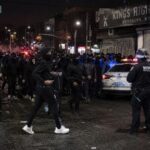 Brooklyn HORROR: Masked Mobs Assault Jewish Children… Crowd of people gathered on a street with police officers and vehicles