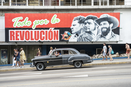 shutterstock_490436281.jpg A mural depicting revolutionary figures with a classic car passing by