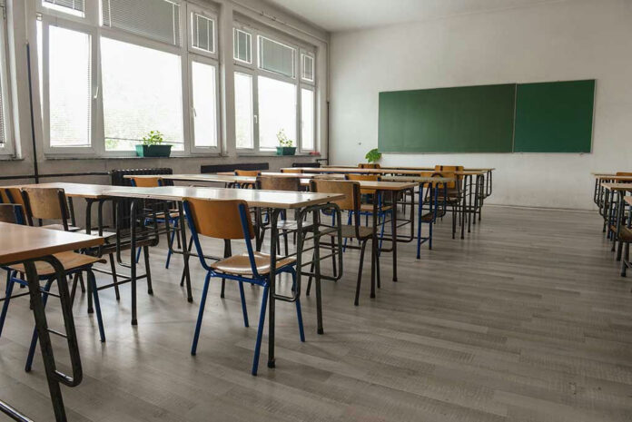 487861393 Empty classroom with desks, chairs, windows, and chalkboard.