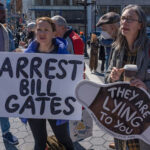 Protesters holding signs at an outdoor demonstration