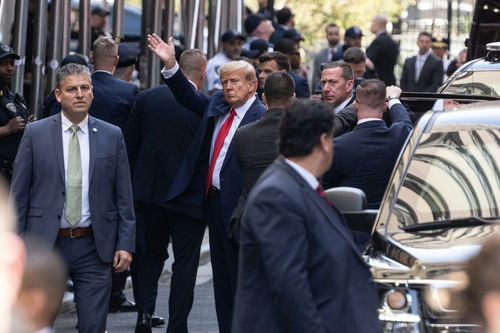 shutterstock2284766697jpg-1 man in suit waving amid security entourage on a busy city street