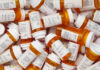 A pile of prescription medication bottles with labels