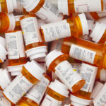 A pile of prescription medication bottles with labels