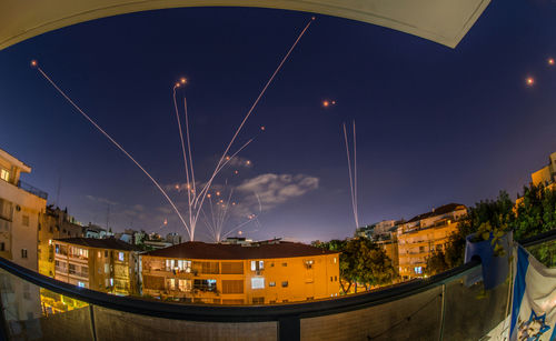 shutterstock_1977677069 Night sky with missile defense system intercepting rockets above city.