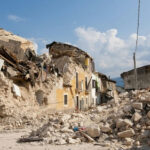 Rubble from collapsed buildings in earthquake-hit area. Clear sky.
