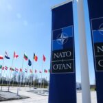 Russia’s Shadow War Tests NATO NATO flags displayed at the headquarters under a clear blue sky