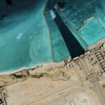 Iran Strikes Ignite Gulf Panic Satellite view of coastal industrial complex with turquoise water