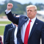 Trump Critic Flips — Over Hostages A political figure raising a fist in a gesture of confidence during an outdoor event