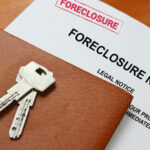Home Theft Ring Exposed In Detroit Keys on a foreclosure notice document and leather folder.