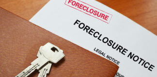 Keys on a foreclosure notice document and leather folder.
